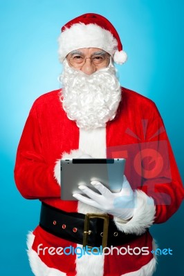 Modern Santa Using Digital Touch Screen Device Stock Photo