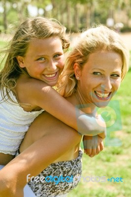 Mom Giving Piggyback Ride To Child Stock Photo