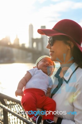 Mom Is Holding Her Baby With The City In The Background Stock Photo