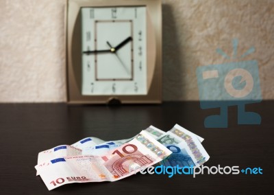 Money On The Table And Wall Clock From Behind Stock Photo