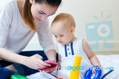 Mother And Baby Girl Using A Smartphone At Home Stock Photo