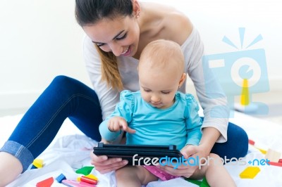 Mother And Baby Girl Using Digital Tablet At Home Stock Photo