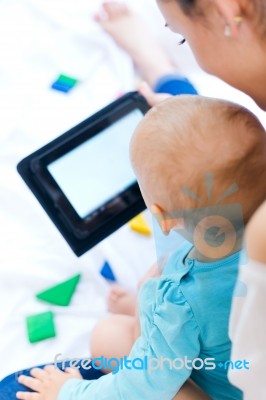 Mother And Baby Girl Using Digital Tablet At Home Stock Photo