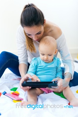 Mother And Baby Girl Using Digital Tablet At Home Stock Photo