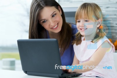 Mother And Daughter Using Laptop In The Kitchen Stock Photo