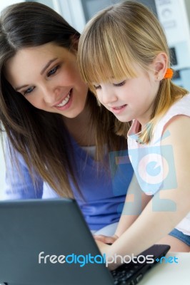 Mother And Daughter Using Laptop In The Kitchen Stock Photo