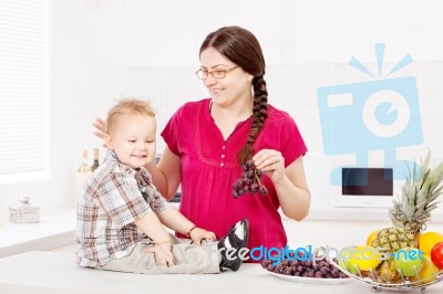 Mother And Son With Fruits In The Kitchen Stock Photo