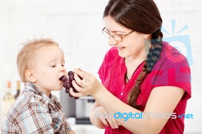 Mother Feeding Child With Grape Stock Photo