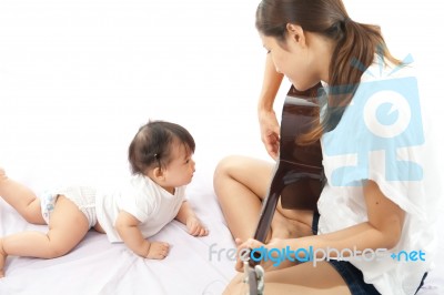 Mother Is Playing A Guitar For Her Baby Stock Photo