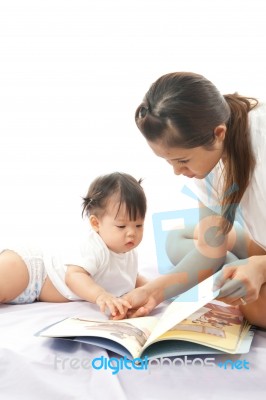 Mother Is Reading A Book For Her Baby Stock Photo