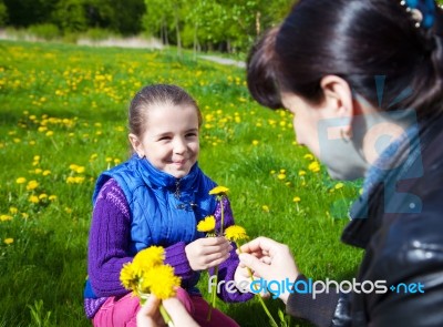 Mother Weaves A Wreath Of Dandelions Stock Photo