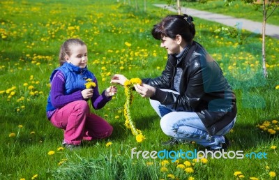 Mother Weaves A Wreath Of Dandelions For Her Daughter Stock Photo