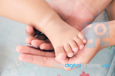 Mother's Hand Cradles The Foot Of A Baby Stock Photo