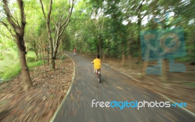 Motion Burred Of Boy Riding Bicycle Through The Forest Stock Photo