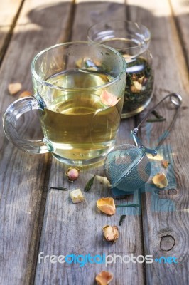 Mug Of Flavored Green Tea With Rose Buds And Petals Stock Photo