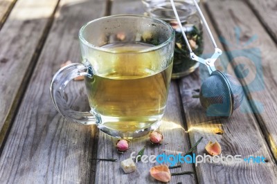 Mug Of Flavored Green Tea With Rose Buds And Petals Stock Photo