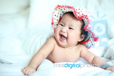 Newborn Baby With Colorful Floppy Hat Lying Down On A White Blan… Stock Photo