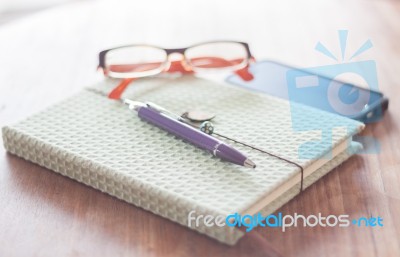 Notebook And Pen With Eyeglasses On Wooden Table Stock Photo