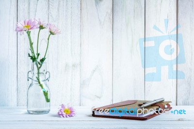 Notebook And Pen With Flower On White Wooden Table Stock Photo