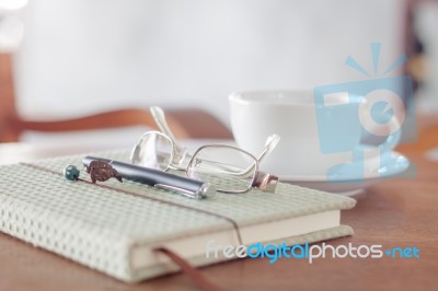 Notebook With Pen, Eyeglasses And White Coffee Cup Stock Photo