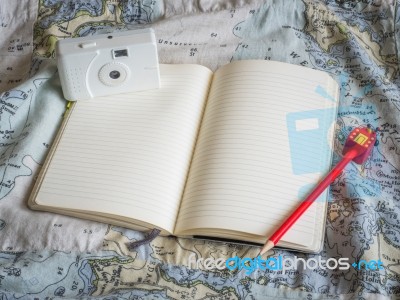 Notebook With Red Pencil And White Film Camera On Map Pattern Stock Photo