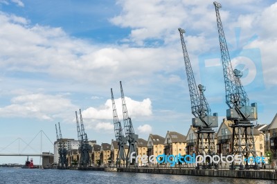 Old Dockside Cranes Alongside A Waterfront Development Stock Photo