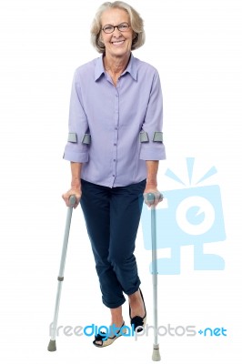 Old Woman Walking With Crutches Stock Photo