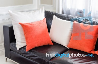 Orange And White Pillows On Modern Black Sofa In Stock Photo