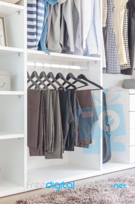 Pants Hanging On Rail In White Wardrobe Stock Photo