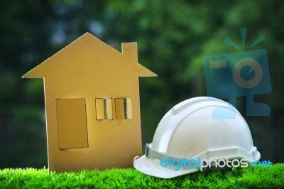 Paper Home Out Line With Safety Helmet On Green Grass Field Wtih… Stock Photo