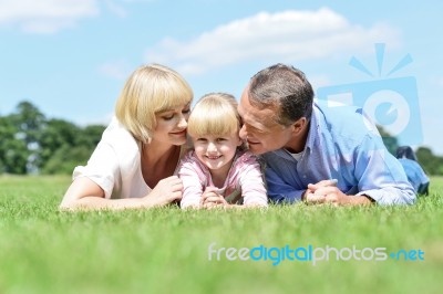 Parents Kissing Their Sweet Angel Stock Photo