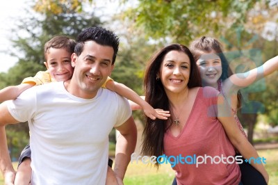 Parents Piggy Back Their Children Stock Photo