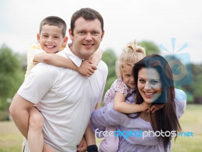 Parents Piggy Backing Kids Stock Photo