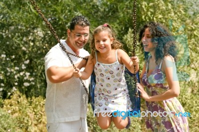 Parents Pushing Swing Gently Stock Photo