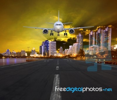 Passenger Air Plane Landing In Urban Airport Against Sunset And Stock Photo