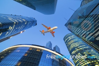 Passenger Jet Airplane Flies Above Skyscrapers Stock Photo