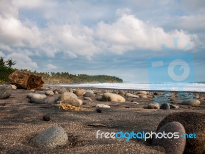 Pebbles On A Beach With A Tree Trunk Stock Photo