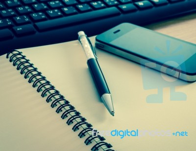 Pen And Cell Phone On A Notebook With Keyboard Stock Photo