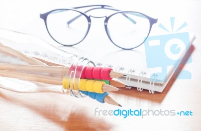 Pencils In Bottle With Eyeglasses On Notebook Stock Photo