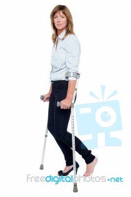 Pensive Looking Woman Using Crutches To Walk Stock Photo