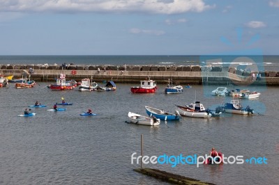 People Enjoying Themselves In Staithes Harbour North Yorkshire Stock Photo