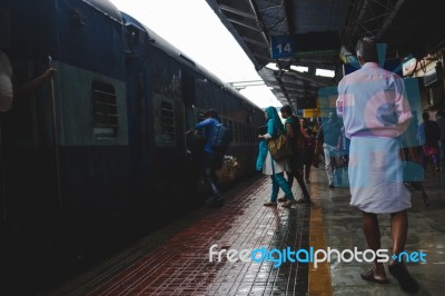 People Rushing To Board A Train As A Man In A Pink Shirt Walks B… Stock Photo