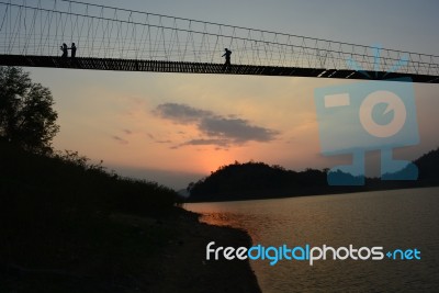 People Walking Across The Bridge With Sunset Stock Photo