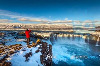 Photoghaper Taking A Photo At Godafoss Waterfall In Winter, Iceland Stock Photo