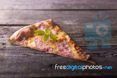 Piece Of Basil On Hot Pizza, Wooden Background Stock Photo