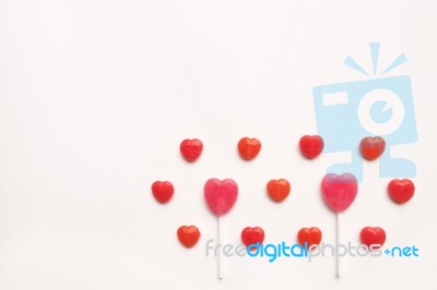 Pink Valentine's Day Heart Shape Lollipop With Small Red Candy In Cute Pattern On Empty White Paper Background. Love Concept. Colorful Hipster Style. Knolling Top View Stock Photo