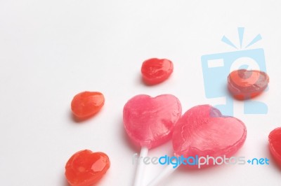 Pink Valentine's Day Heart Shape Lollipop With Small Red Candy In Cute Pattern On Empty White Paper Background. Love Concept.  Minimalism Colorful Hipster Style Stock Photo