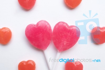 Pink Valentine's Day Heart Shape Lollipop With Small Red Candy In Cute Pattern On Empty White Paper Background. Love Concept. Colorful Hipster Style. Knolling Top View Stock Photo