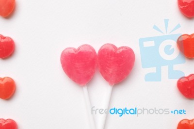 Pink Valentine's Day Heart Shape Lollipop With Small Red Candy In Cute Pattern On Empty White Paper Background. Love Concept. Colorful Hipster Style. Knolling Top View Stock Photo