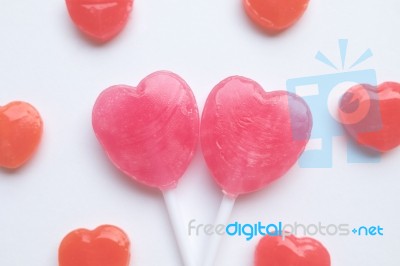 Pink Valentine's Day Heart Shape Lollipop With Small Red Candy In Cute Pattern On Empty White Paper Background. Love Concept. Colorful Hipster Style. Knolling Top View Stock Photo